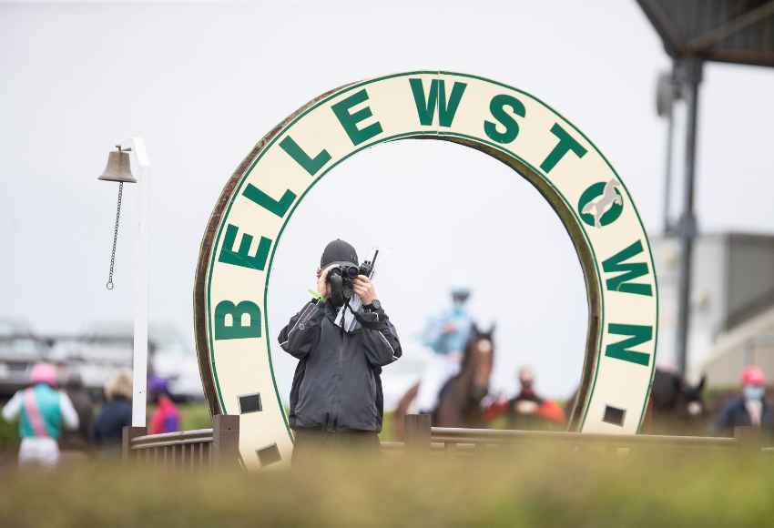 Racecourse staff standing under horse shoe shaped Bellewstown sign with binoculars at Bellewstown Racecourse