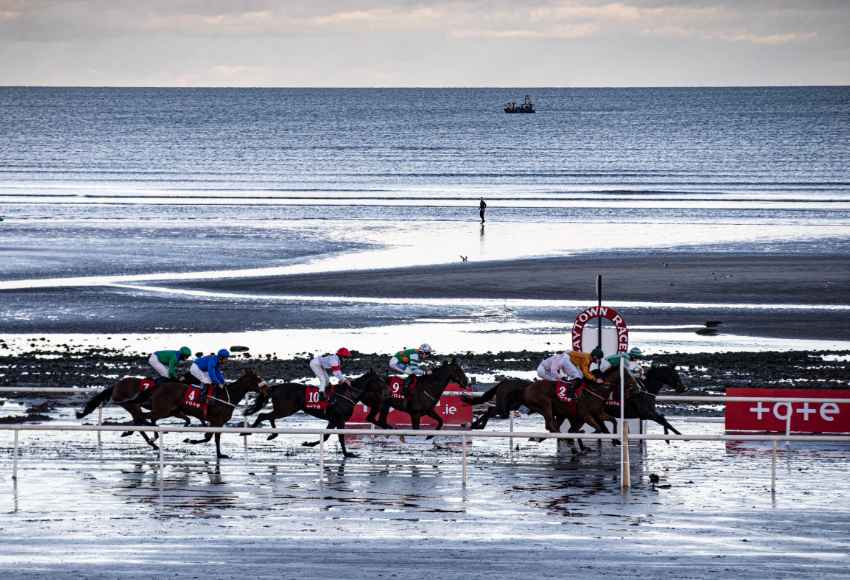 Horses running on the beach track at Laytown Racecourse with the sea in the background