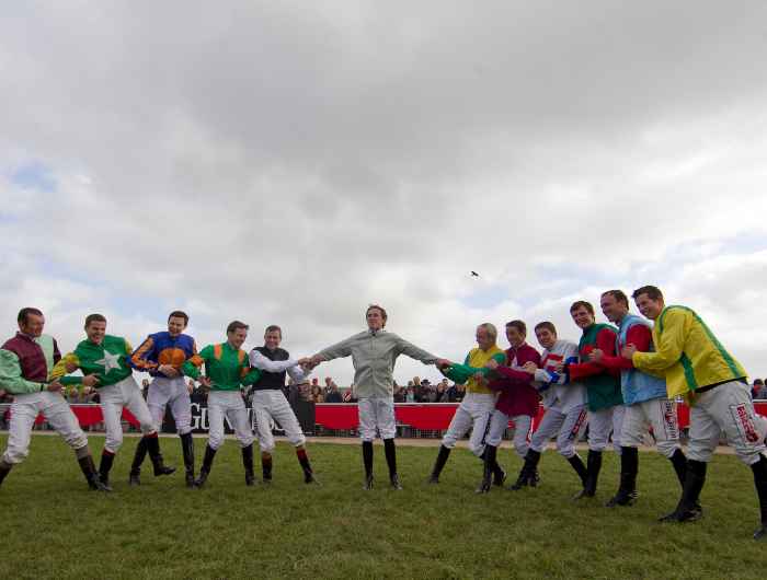 Numerous jockeys out posing before a charity race